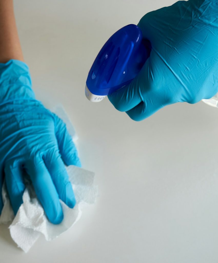 person in blue gloves holding white textile